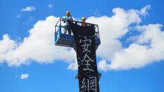 高空作業車上的工會成員垂放「安全網」黑色布條